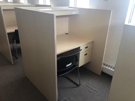 Grad carrel. On upper floors, along an outer wall, near windows. Desk with side panels on either side for privacy. A lockable desk drawer. Not much space under desk.