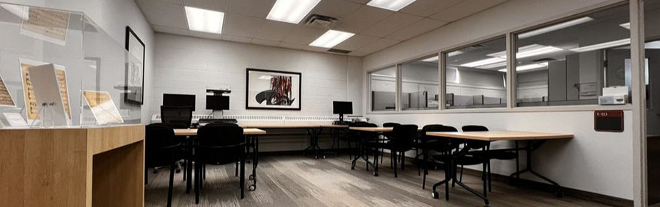 Laurier Archives and Special Collections reading room, featuring a display case, tables, chairs, two computers, and a book scanner.