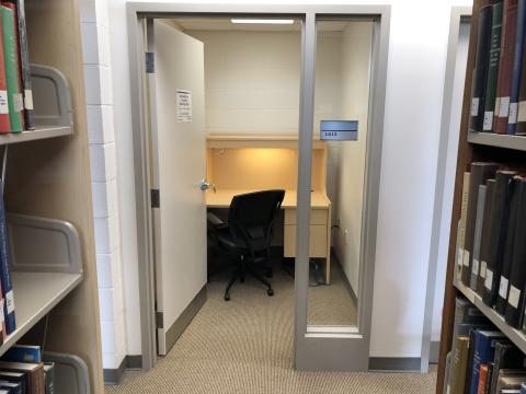 A private study room. There's a desk with large surface and chair. Braille on door signs.