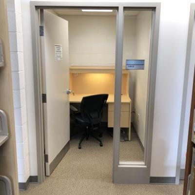 A private study room. There's a desk with large surface and chair. Braille on door signs
