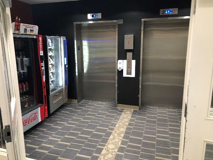 Through a set of doors are vending machines, on the left, and then two elevators.