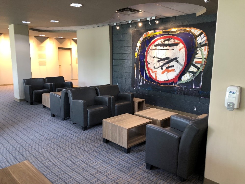 A comfortable seating area. Two comfy chairs next to each facing two other comfy chairs. Square coffee tables in between them.