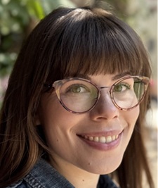 A woman with glasses smiling gently into the camera
