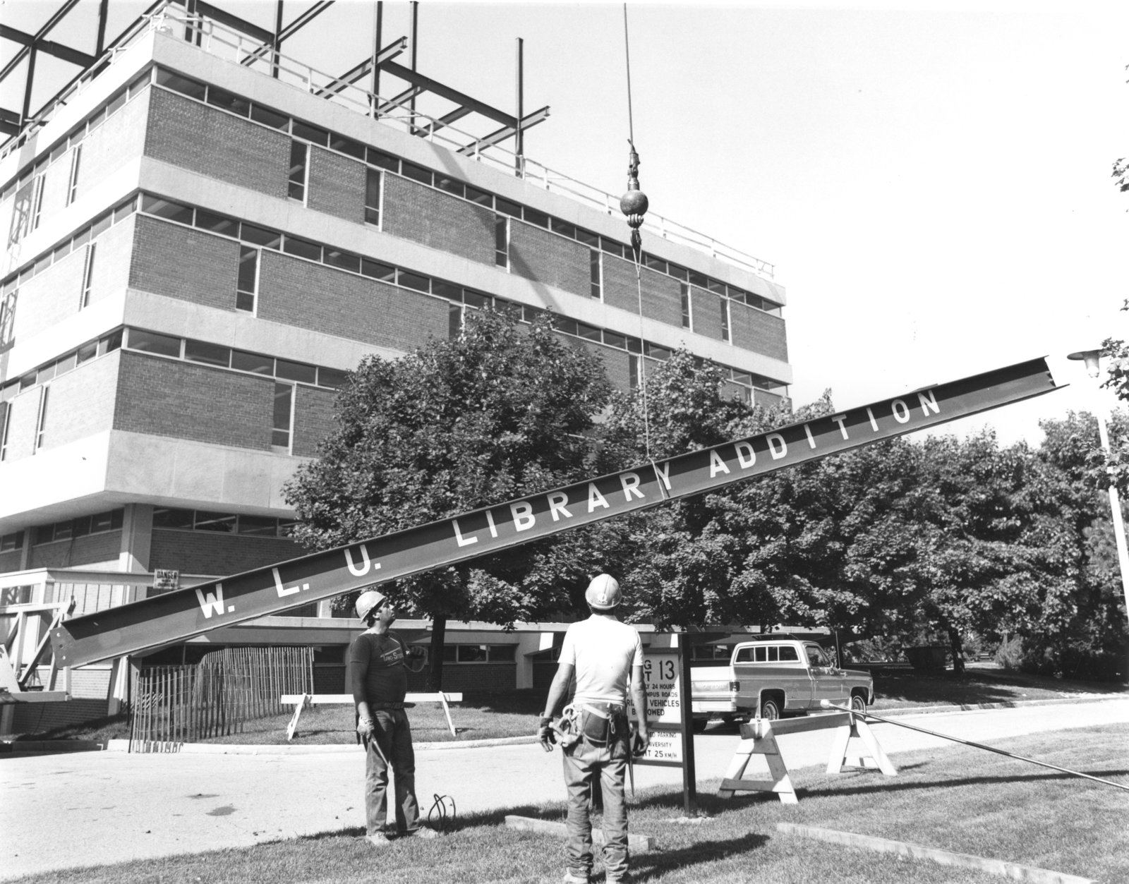 Construction crew at the Laurier Library looking at material being lifted by a crane