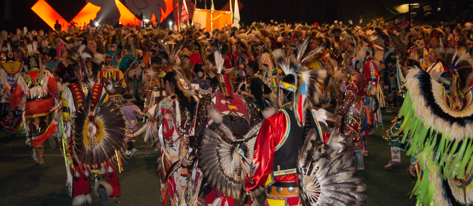A large gathering of First Nations, Metis and Inuit in full regalia.