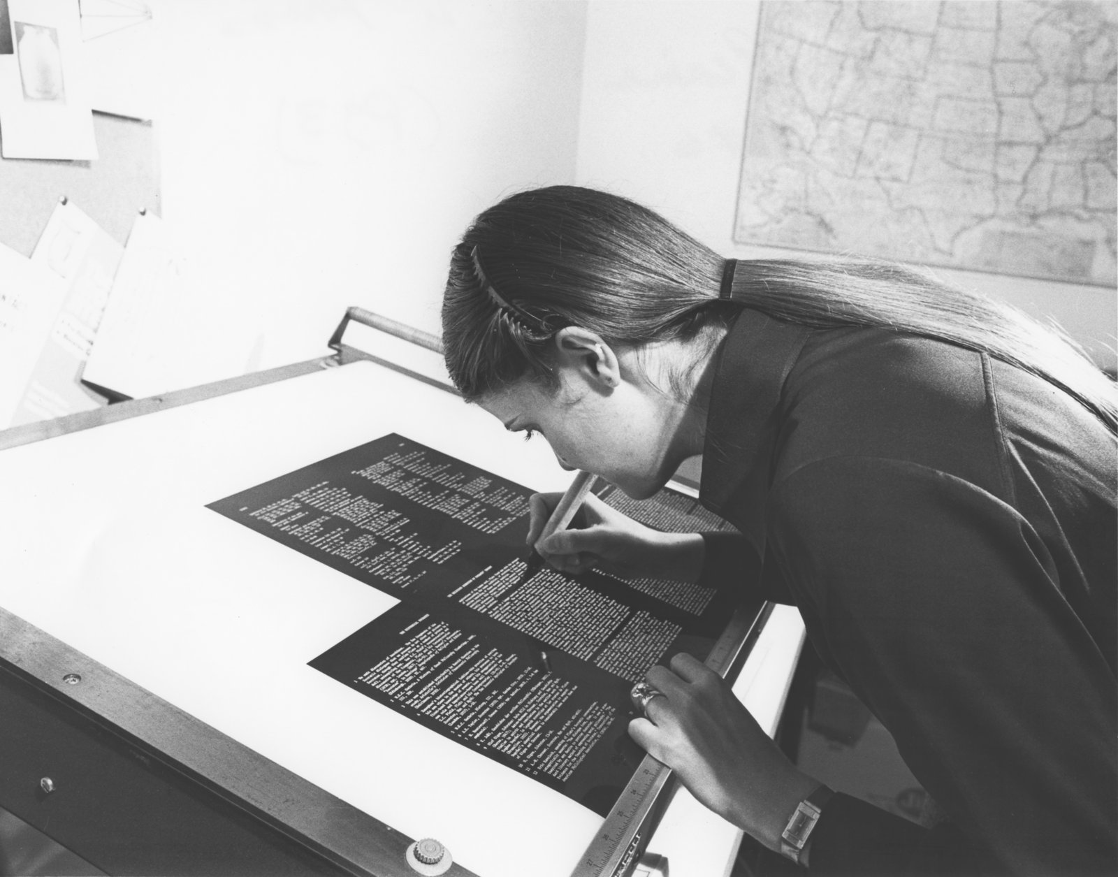 WLU Press staff member Heather Blaine working at a light table with pages