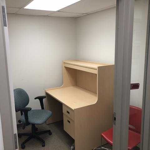 A private study room. There's a desk with large surface and chair. Braille on door signs.